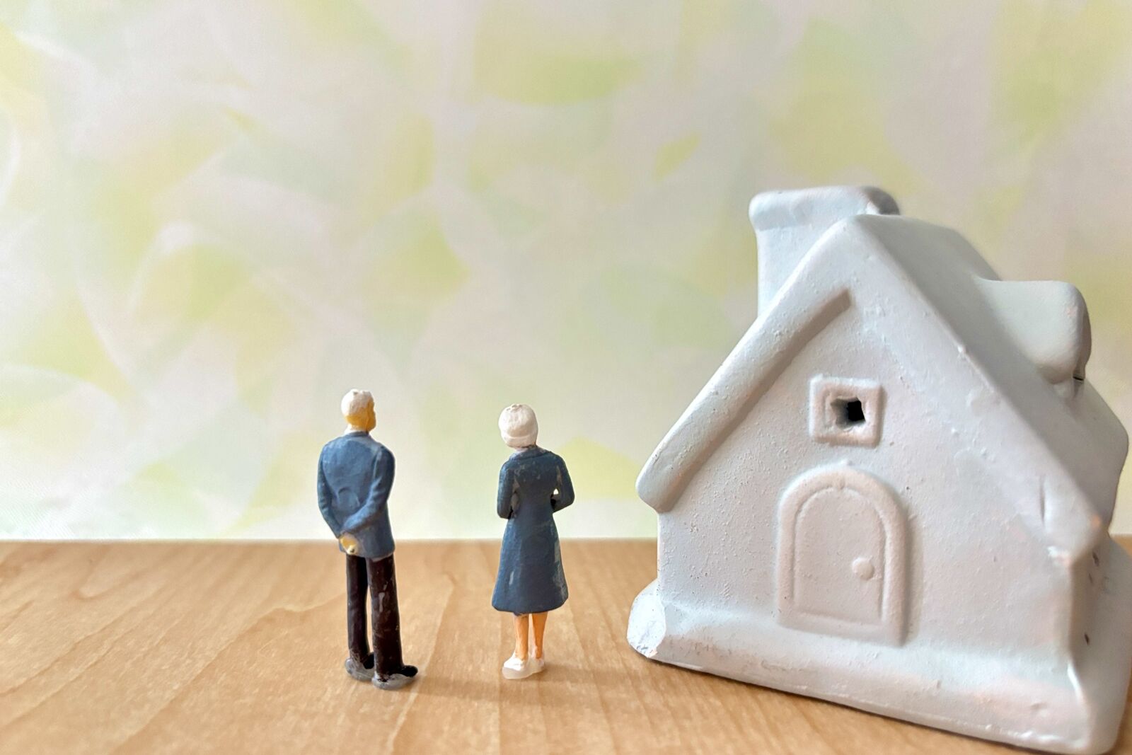 ミニチュアのご夫婦人形が、住まいの模型を見つめる後ろ姿